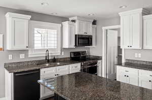 Kitchen with appliances with stainless steel finishes, white cabinets, dark stone counters, and recessed lighting