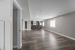 Empty room with dark wood-style flooring, a textured ceiling, and recessed lighting