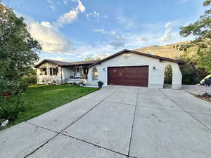 Ranch-style home featuring driveway, a front yard, a porch, brick siding, and an attached garage