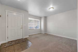 Foyer with tile patterned flooring, carpet, and a textured ceiling