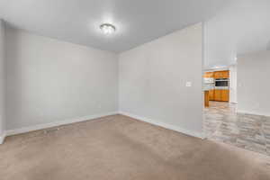 Unfurnished room with baseboards and light carpet