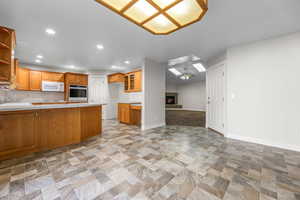 Kitchen featuring a tiled fireplace, a peninsula, recessed lighting, light countertops, and open floor plan