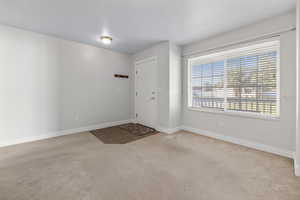Foyer entrance with light carpet and baseboards