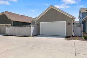 View of front of home featuring board and batten siding, a garage, a gate, and driveway