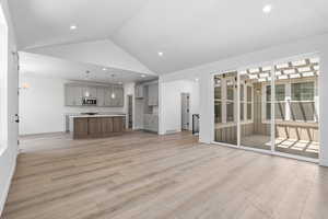 Unfurnished living room with vaulted ceiling, light wood-style flooring, and recessed lighting