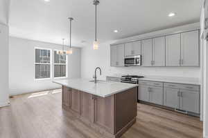 Kitchen with stainless steel appliances, gray cabinets, a chandelier, recessed lighting, and light countertops