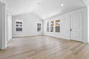 Unfurnished living room featuring light wood-style flooring, lofted ceiling, and recessed lighting