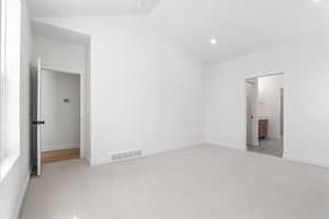 Unfurnished bedroom featuring lofted ceiling, light carpet, recessed lighting, and connected bathroom