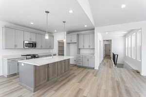 Kitchen with appliances with stainless steel finishes, gray cabinetry, recessed lighting, light countertops, and light wood-type flooring