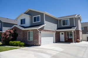 View of front of property with an attached garage, brick siding, and concrete driveway