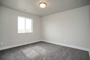 Spare room with dark colored carpet and baseboards