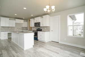 Kitchen featuring appliances with stainless steel finishes, backsplash, a chandelier, white cabinetry, and recessed lighting