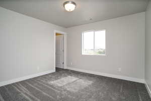 Carpeted spare room featuring baseboards