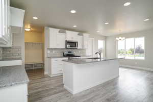 Kitchen featuring stainless steel appliances, tasteful backsplash, white cabinetry, recessed lighting, and light wood-style flooring