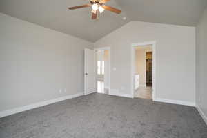 Unfurnished bedroom featuring lofted ceiling, carpet floors, a walk in closet, and a ceiling fan