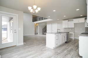 Kitchen featuring tasteful backsplash, white cabinetry, light wood-style floors, decorative light fixtures, and recessed lighting