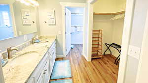 En suite bathroom with double vanity, wood finished floors, and a spacious closet