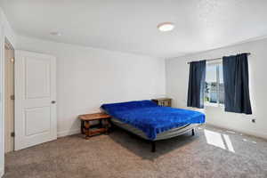 Carpeted bedroom with a textured ceiling and baseboards