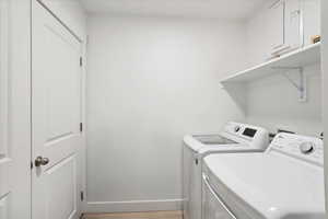 Washroom with light wood finished floors and washing machine and dryer