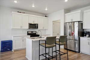 Kitchen with appliances with stainless steel finishes, light wood-style flooring, white cabinetry, and recessed lighting