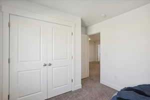 Bedroom with dark colored carpet and a closet
