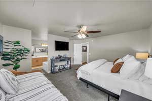 Bedroom featuring dark carpet, connected bathroom, and ceiling fan