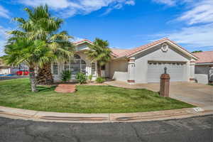 Mediterranean / spanish-style home with an attached garage, a tiled roof, a front lawn, driveway, and stucco siding