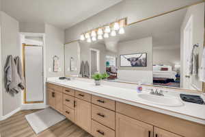 Ensuite bathroom with wood finished floors, double vanity, and a stall shower