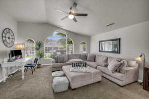 Living area featuring ceiling fan, carpet flooring, lofted ceiling, a desk, and a textured ceiling