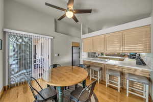 Dining room featuring ceiling fan, light wood-type flooring, and high vaulted ceiling