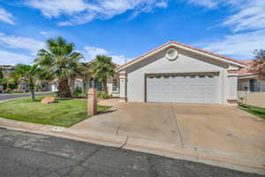 Mediterranean / spanish house featuring stucco siding, a tile roof, an attached garage, driveway, and a front lawn