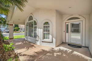 View of exterior entry featuring stucco siding and covered porch