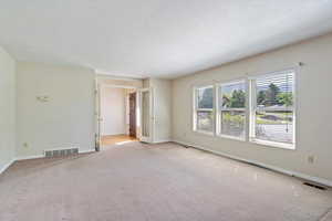 Carpeted empty room featuring baseboards and a textured ceiling