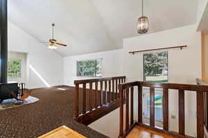 Staircase featuring a wood stove, healthy amount of natural light, ceiling fan, and high vaulted ceiling