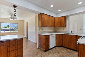 Kitchen featuring dishwasher, brown cabinets, light countertops, ceiling fan, and decorative light fixtures