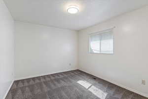 Unfurnished room featuring dark carpet and a textured ceiling