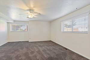 Carpeted spare room featuring a textured ceiling and ceiling fan