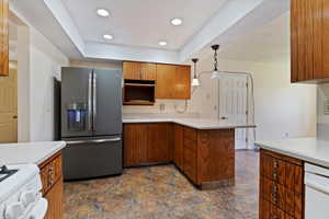 Kitchen featuring stainless steel refrigerator with ice dispenser, stove, white dishwasher, a peninsula, and brown cabinets