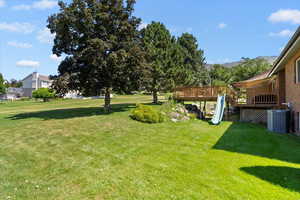 View of green lawn featuring a deck with mountain view