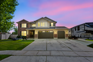 Traditional-style house with brick siding, driveway, a garage, stucco siding, and a shingled roof