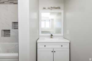 Bathroom with vanity and a combined bath / shower with jetted tub