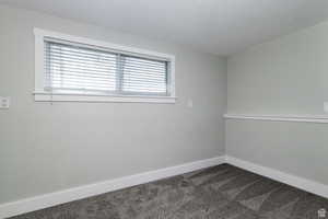 Spare room featuring dark colored carpet and a textured ceiling