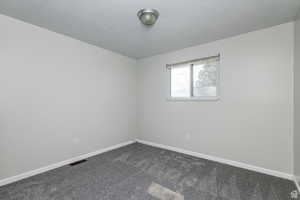 Empty room featuring dark colored carpet and baseboards