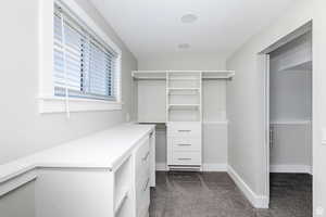 Walk in closet with dark colored carpet