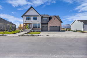 Modern inspired farmhouse with board and batten siding, driveway, brick siding, a mountain view, and a standing seam roof