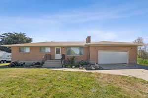 Single story home with brick siding, a front yard, an attached garage, concrete driveway, and a chimney