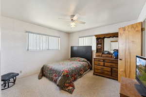 Carpeted bedroom with wallpapered walls and a ceiling fan