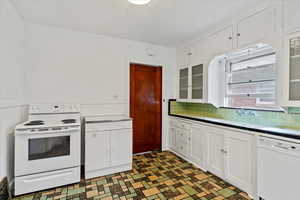 Kitchen featuring white cabinets, white appliances, tasteful backsplash, glass insert cabinets, and a textured ceiling