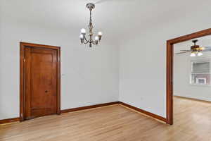 Unfurnished dining area with light wood finished floors, a chandelier, and a ceiling fan