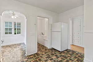 Kitchen with freestanding refrigerator, ceiling fan, and brick patterned flooring